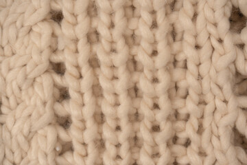 A fragment of beige knitted fabric, knitted from white sheep wool.