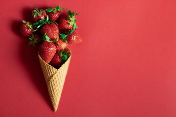 Fresh strawberries in an ice cream cone on a bright red background. The concept of spring and...