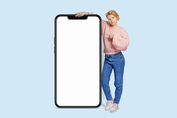 Full body side view young woman wear pink casual sweater huge big  blank screen mobile cell phone with area use smartphone isolated on plain pastel light background.