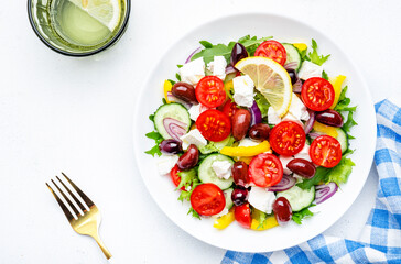 Traditional greek salad with feta cheese, kalamata olives, tomatoes, paprika, cucumber and onion, healthy mediterranean diet food. White table background, top view