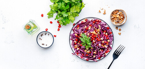 Vegan red cabbage salad with parsley, juicy pomegranate, crunchy walnuts on white kitchen table background. Healthy diet food. Top view banner