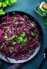 Healthy vegan vegetable salad with red cabbage, parsley and olive oil on blue kitchen table background, top view