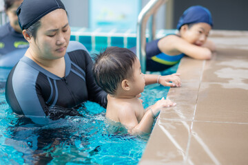 Happy kindergarten asian boy swimming with mom in condominium swimming pool
