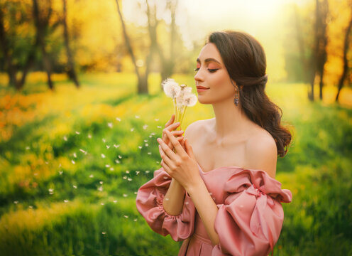 Art photo happy woman holding blowing on dandelion flowers in her hands. Fantasy girl princess enjoys nature, beautiful joyful smiling face. Forest green grass lawn glade trees bright magic sun light