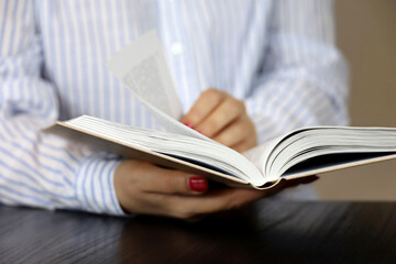 Woman reading a book while sitting at table. Concept of education and literature
