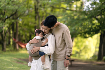 新緑の公園で赤ちゃんに話しかけるお父さんとお母さん