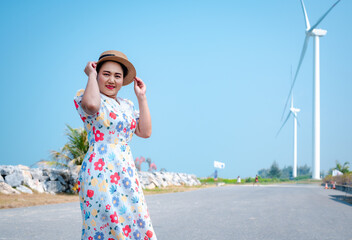 Portrait of a senior Asian woman in summer dress and straw hat and looking at camera on the beach