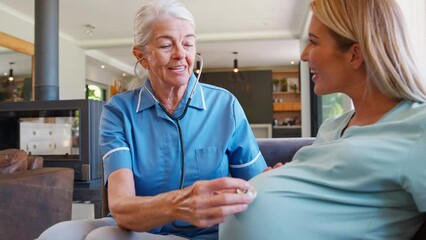 Senior midwife with stethoscope visiting pregnant woman at home with family in background - shot in slow motion - Powered by Adobe
