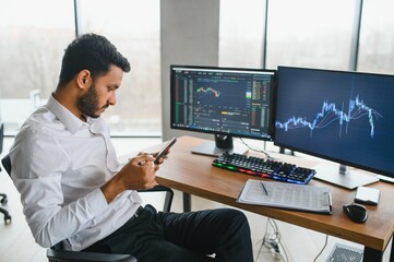 Thoughtful concentrated indian business man entrepreneur investor manager using computer, watching...