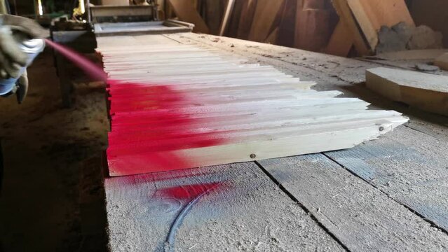 Spray painting wooden warning stakes with red color paint