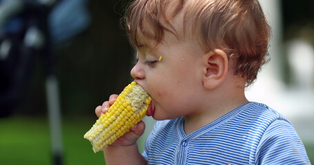 Cute baby eating corn cob outside