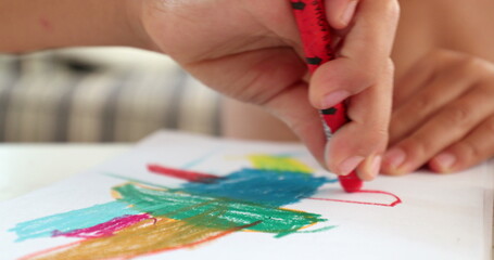 Obraz premium Closeup child hands drawing on paper with crayon