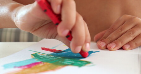 Naklejka premium Closeup child hands drawing on paper with crayon