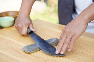 Closeup man hands sharpen knife on whetstone sharpener or grindstone. Concept, maintenance tools...