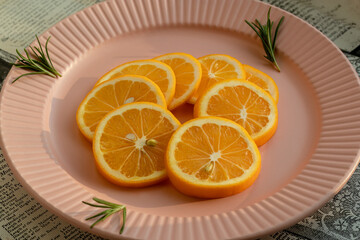 Sliced lemon on pink plate. With rosemary sprigs