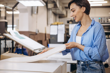 Woman working in printing house with paper and paints