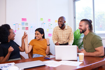 Development team members high five and celebrate, launch of new app success