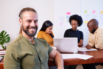 Portrait of smiling white man with ponytail, creative coding team brainstorm