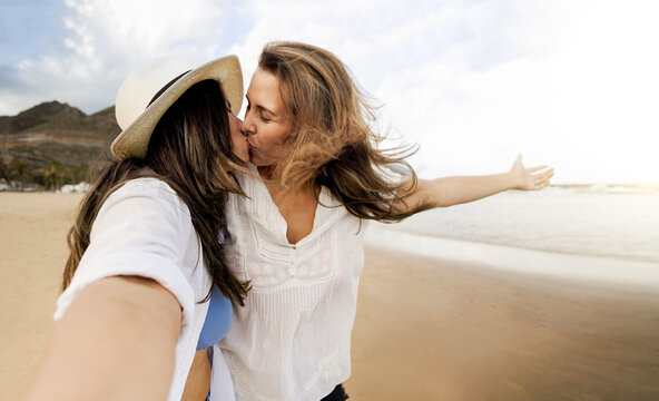 Happy gay lesbian couple kissing at the beach - Lgbt women taking selfie picture with mobile phone outside - Summer travel lifestyle concept