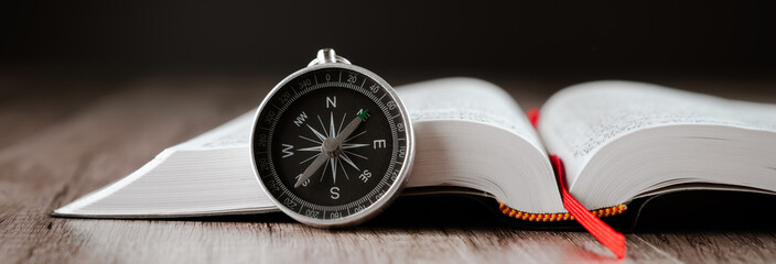 Book and compass on the table - obrazy, fototapety, plakaty