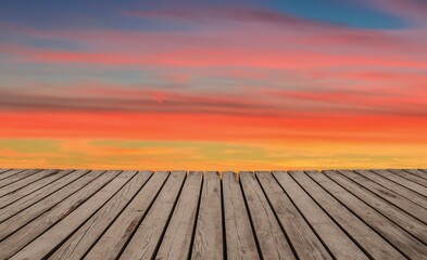 Idea with a colored background and boards to insert your item. Wooden planks floor with sunset color sky in the background.