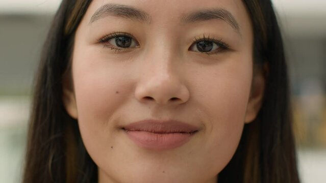 Extreme close up Asian woman face head shot portrait korean japanese chinese girl beauty treatment natural makeup eyebrows smile friendly expression female lady student businesswoman looking at camera