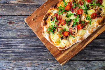 Pinsa Romana with bacon, mozzarella cheese and mushrooms on wooden table  © Jacek Chabraszewski