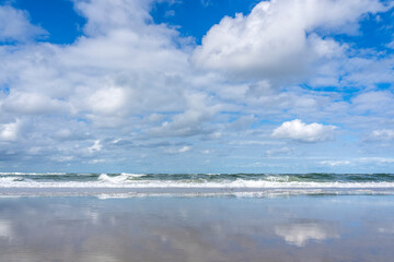 Beautiful clouds over the surf, reflected in the receding water on the beach, on the north side of Vlieland