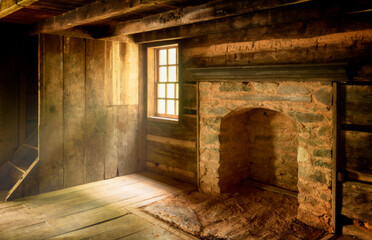 Rustic log cabin interior with light rays throughout the windows and wood floors 