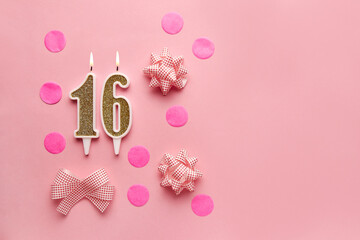 Number 16 on pastel pink background with festive decor. Happy birthday candles. The concept of...