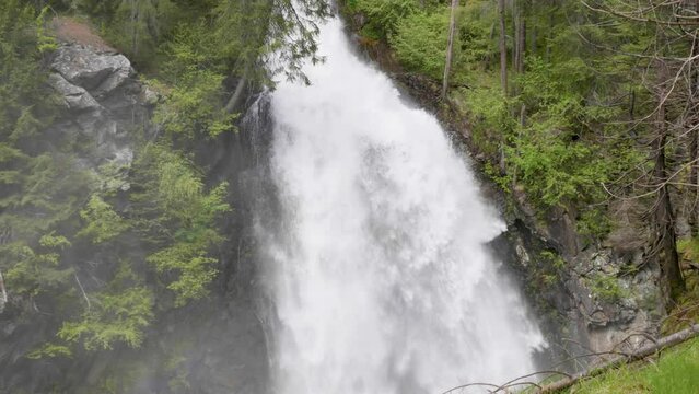 video slow motion di una cascata in un bel bosco di montagna con conifere, i panorami delle dolomiti e l'effetto seta della cascata