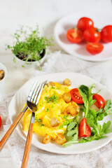 American scramble omelet with arugula, tomatoes and mushrooms, next to a plate with mushrooms and tomatoes