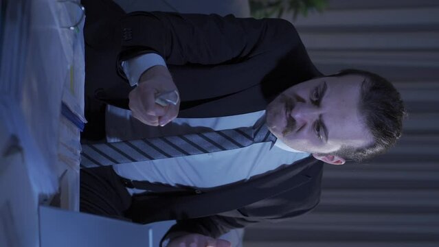 Vertical Video of Psycho businessman does schizophrenia gestures at home at night.