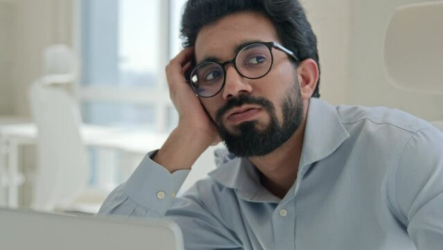 Sleepy tired Arabian Indian man businessman lazy worker employee manager working boring online job in office feel depression burnout low energy apathy fatigued overwork unwell male guy with weariness 