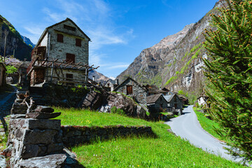 Fototapeta na wymiar The typical houses of the Val Maggia mountain countries with its mountains and woods during a spring day, near the town of Foroglio, Switzerland - May 2023