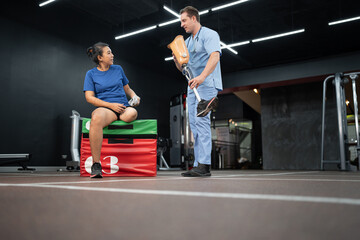 Naklejka na ściany i meble Caucasian assisted male physiotherapist take care Asia woman with prosthetic leg 