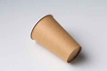 Disposable cardboard biodegradable glass on a white table, gray background.