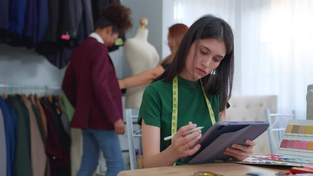 Diverse tailor women fashion designer work design clothes in tailoring atelier. Team female dressmaker team feel happy and enjoy design new pattern collection ideas. professional small business.