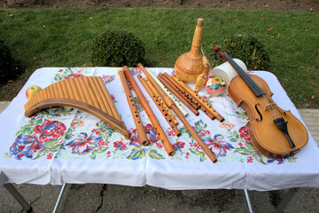 Handmade folk wooden instrument violin flute on colored tablecloth with flowers