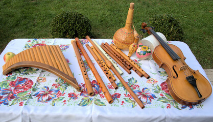 Table with wooden hand made folk instruments violin flute white tablecloth background