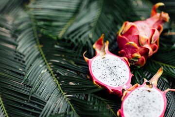 Fresh exotic fruits on green tropical palm leaves background. Sliced dragon fruit. flat lay,...