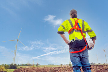 male engineers wearing safety jackets looking at power generation turbines planwork to inspect and repair wind turbines lead wind power produce electricity in the turbine field.renewable energy concep