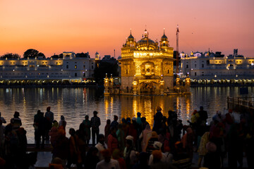 Golden temple in Amritsar at sunset with people silhouettes in front