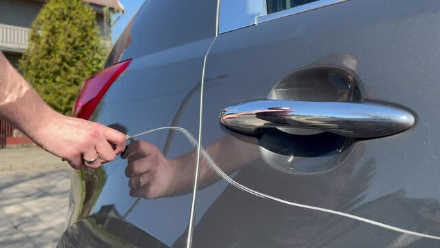 Man hand scratching a car body surface with a key. Devastation, destroying an expensive car on purpose.
