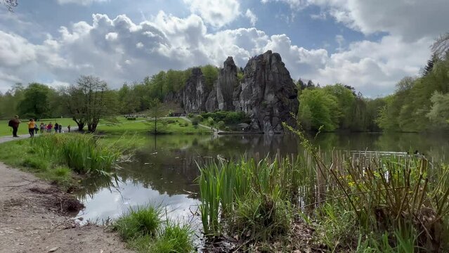 Externsteine, Germany - 05.05.2023: Beautiful fairytale landscape of Externsteine stones with a lake. Fantasy view of german nature with some ducks passing by.