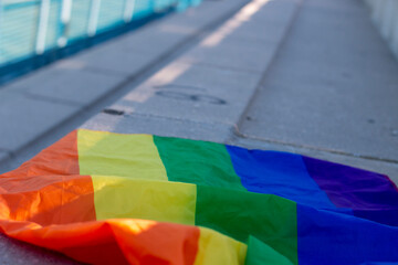 Gay pride flag on a concrete bleacher of a soccer field, held by the fist or hand of a person