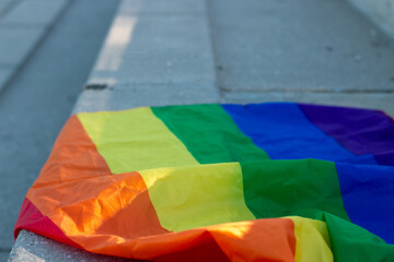 Gay pride flag on a concrete bleacher of a soccer field, held by the fist or hand of a person