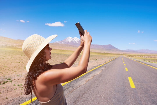 brunette woman standing on the road taking photos selfies in San Pedro de Atacama