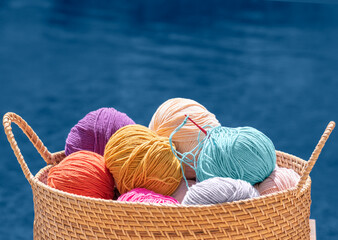 Knitting, crochet, needlework. Still life photo with multicolored wool skeins of yarn in basket...
