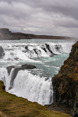 Golden waterfall (Gullfoss falls in Icelandic language). Landscape photo video with this landmark waterfall during a cloudy day in Iceland.
